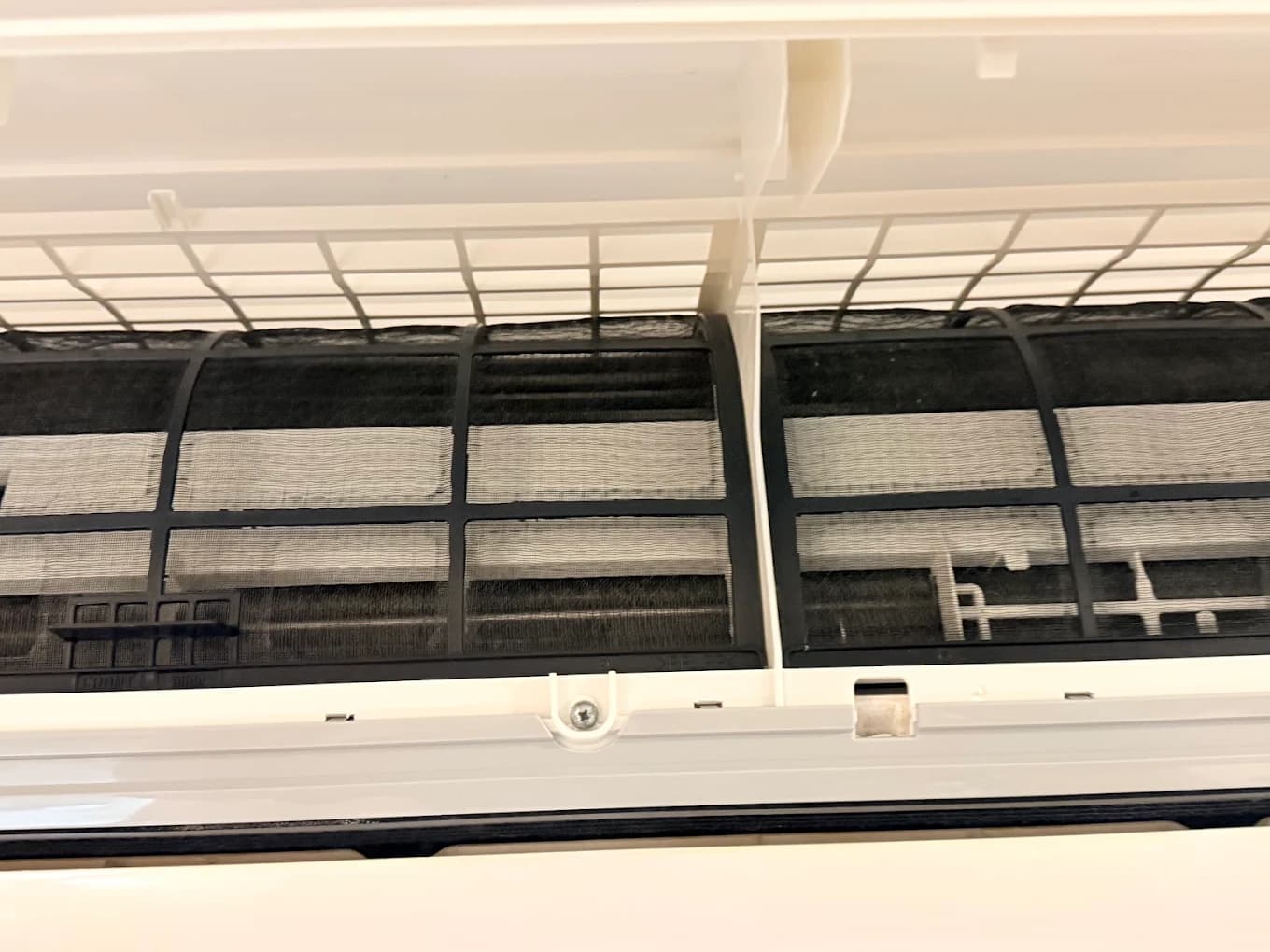 Close-up of a dusty aircon filter mesh before cleaning